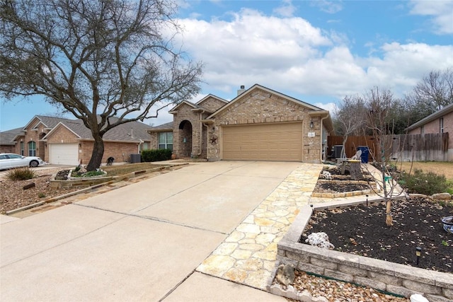 view of front facade with driveway, brick siding, an attached garage, and fence