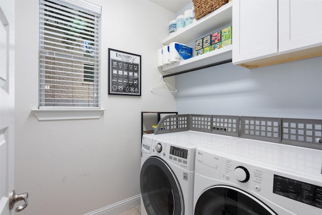 clothes washing area with washer and clothes dryer, cabinet space, and baseboards