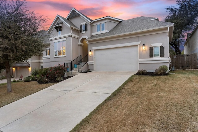 traditional-style house with a shingled roof, a front lawn, concrete driveway, and stucco siding