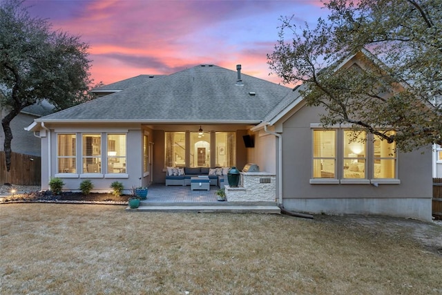 rear view of property featuring an outdoor hangout area, a shingled roof, a lawn, and fence