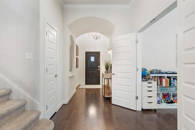 entryway featuring ornamental molding, arched walkways, dark wood finished floors, and stairs