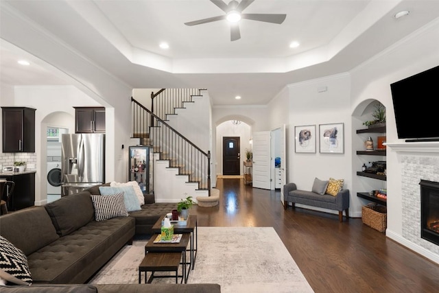 living room with washer / dryer, arched walkways, and a tray ceiling