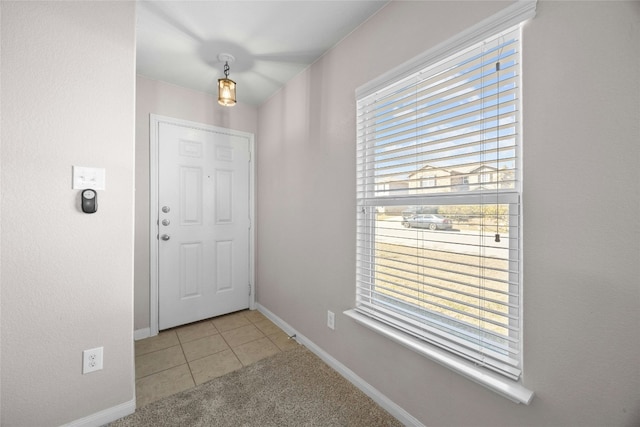 foyer with light colored carpet, a healthy amount of sunlight, and baseboards