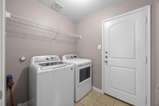 washroom featuring laundry area, light tile patterned floors, visible vents, and washer and dryer