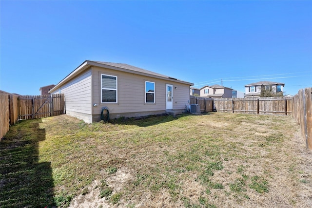 rear view of property with central AC, a yard, and a fenced backyard