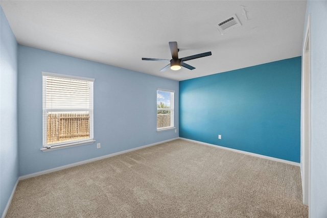 unfurnished room with carpet floors, a ceiling fan, visible vents, and baseboards