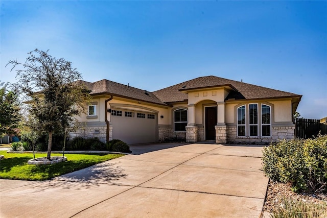 view of front of house featuring an attached garage, stone siding, and stucco siding