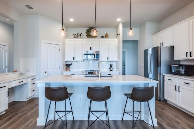 kitchen with visible vents, a breakfast bar area, white cabinets, stainless steel appliances, and a sink