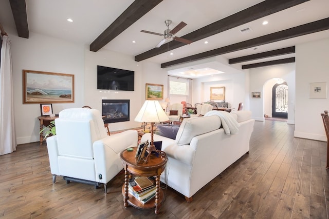 living area featuring arched walkways, dark wood-style flooring, visible vents, and baseboards