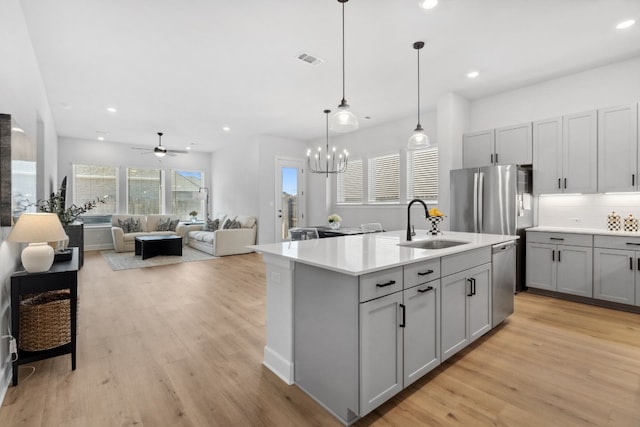 kitchen with a kitchen island with sink, gray cabinetry, visible vents, open floor plan, and light countertops