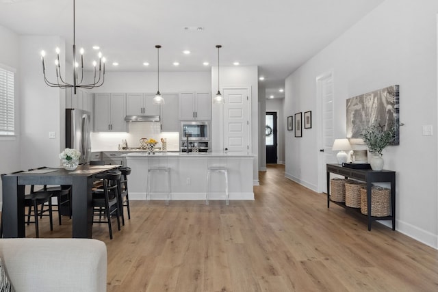 kitchen with stainless steel appliances, light countertops, hanging light fixtures, and a kitchen bar