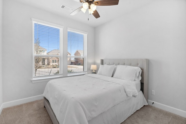 bedroom with a ceiling fan, visible vents, light carpet, and baseboards