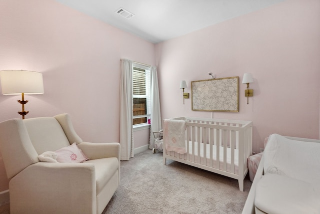 bedroom featuring light carpet, a nursery area, baseboards, and visible vents