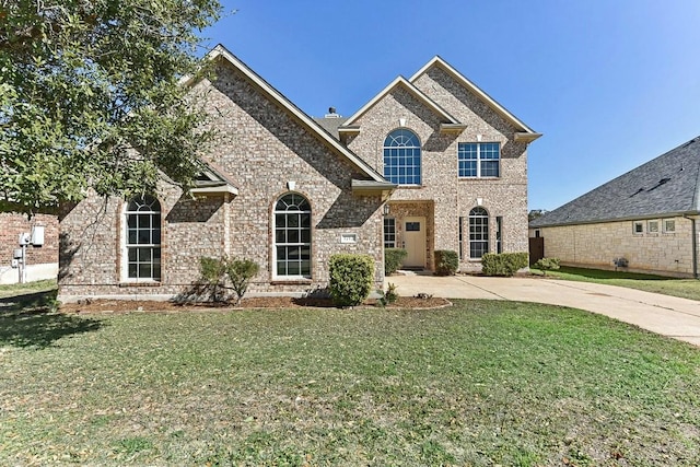 view of front of home with concrete driveway, brick siding, a chimney, and a front yard