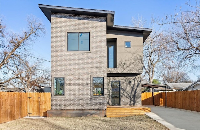 rear view of house with entry steps, fence, and brick siding