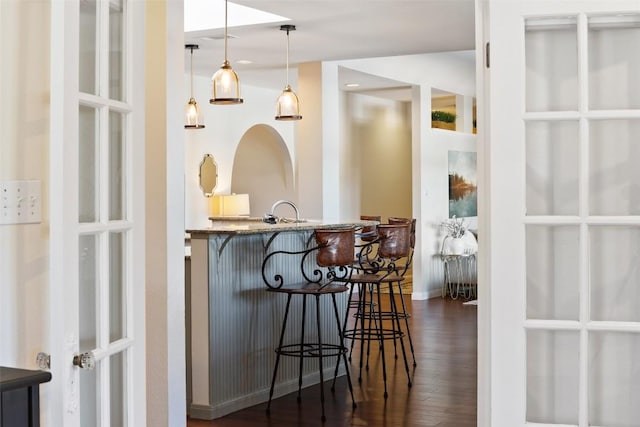 bar with dark wood-style floors and pendant lighting