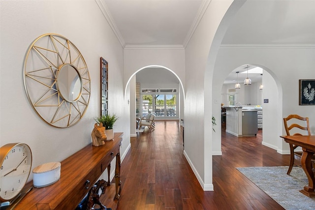 hall with dark wood-style floors, baseboards, arched walkways, and ornamental molding