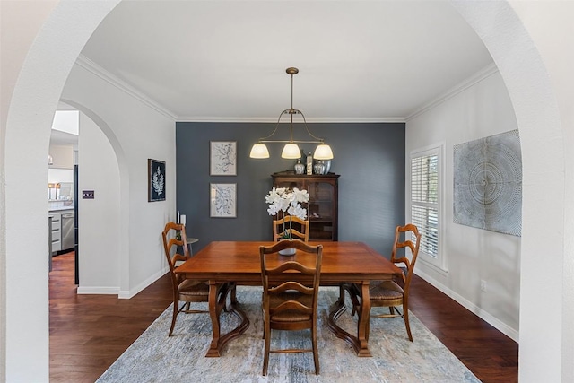 dining room featuring arched walkways, crown molding, dark wood finished floors, and baseboards