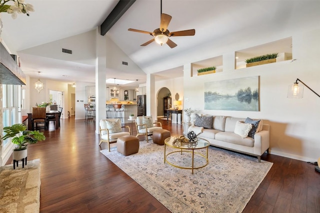 living room featuring arched walkways, ceiling fan with notable chandelier, dark wood-type flooring, baseboards, and beam ceiling