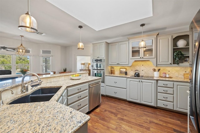 kitchen featuring a sink, hanging light fixtures, gray cabinets, and glass insert cabinets