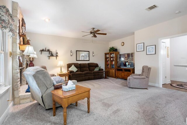 living area featuring visible vents, ceiling fan, light carpet, and baseboards