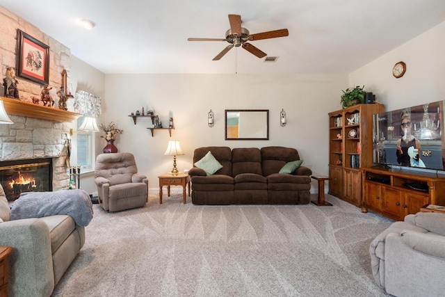 living area featuring a ceiling fan, visible vents, light colored carpet, and a stone fireplace