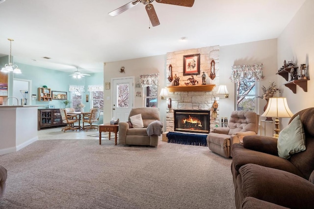 carpeted living area featuring baseboards, a stone fireplace, a wealth of natural light, and a ceiling fan