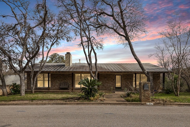 mid-century modern home featuring brick siding, a lawn, and a chimney