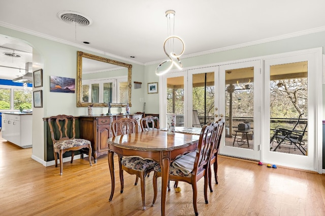 dining room featuring light wood-style floors, french doors, visible vents, and crown molding