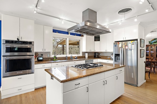 kitchen featuring stone counters, a center island, island exhaust hood, appliances with stainless steel finishes, and white cabinetry