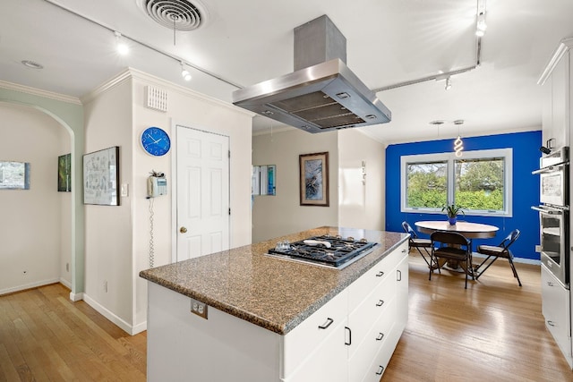 kitchen with a kitchen island, island exhaust hood, white cabinetry, and stainless steel gas stovetop