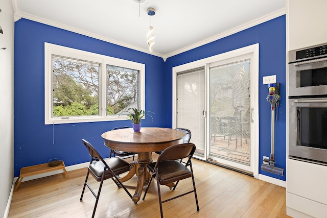 dining space with ornamental molding, baseboards, and light wood finished floors