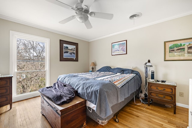 bedroom with crown molding, visible vents, light wood-style floors, ceiling fan, and baseboards