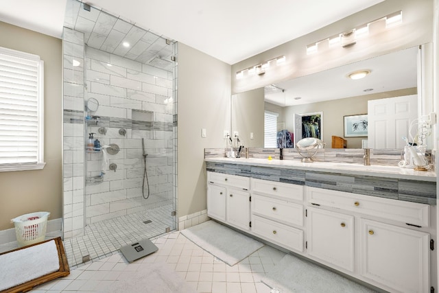 bathroom featuring tile patterned flooring, a shower stall, baseboards, and double vanity