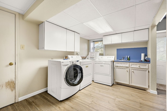 laundry area with light wood-type flooring, washer and dryer, cabinet space, and baseboards