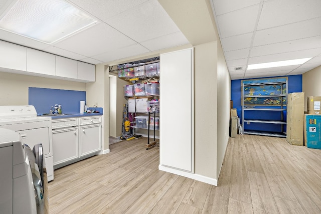 clothes washing area with light wood-style floors, cabinet space, a sink, and baseboards