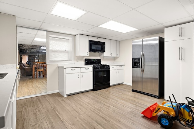 kitchen with black appliances, light wood-style floors, light countertops, and white cabinets