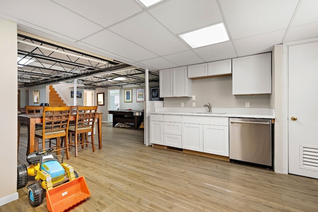 kitchen featuring a sink, white cabinetry, light countertops, stainless steel dishwasher, and light wood finished floors