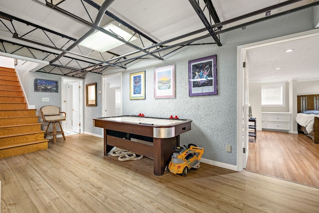 rec room with light wood-type flooring, a textured wall, and baseboards