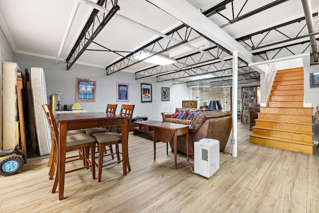 dining room with light wood-type flooring, stairs, and a textured wall