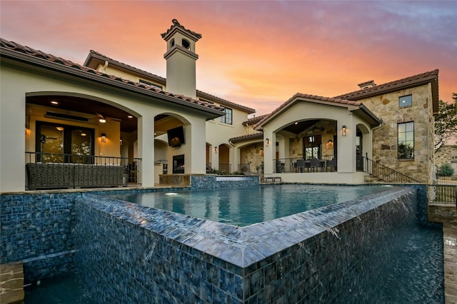 view of swimming pool with an infinity pool, a patio, and a hot tub