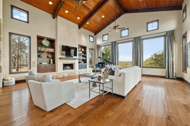 living room with a fireplace, light wood-type flooring, wooden ceiling, beamed ceiling, and baseboards