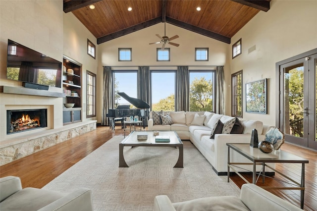 living area featuring light wood finished floors, wooden ceiling, a fireplace, and beam ceiling