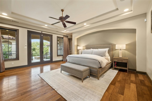 bedroom with access to exterior, a raised ceiling, french doors, and hardwood / wood-style flooring