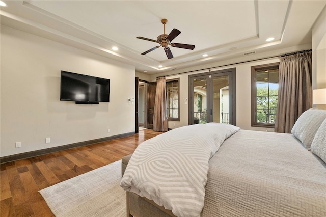 bedroom with access to outside, baseboards, a raised ceiling, and wood finished floors