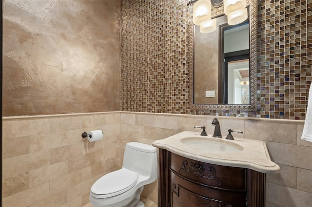 bathroom with toilet, tile walls, and vanity