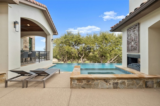 outdoor pool featuring fence, an outdoor fireplace, a patio, and an in ground hot tub