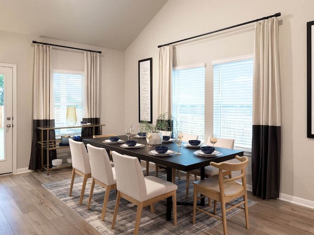 dining room featuring lofted ceiling, light wood-style floors, and baseboards