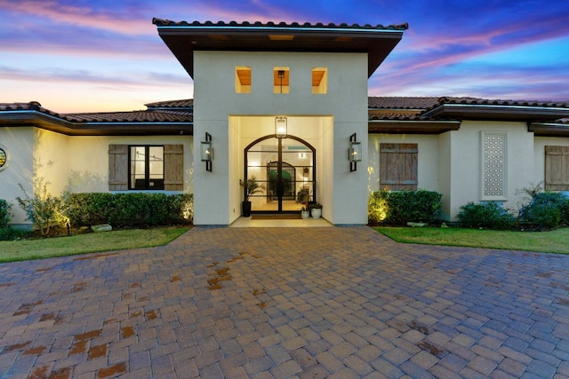 exterior space featuring a tile roof and stucco siding