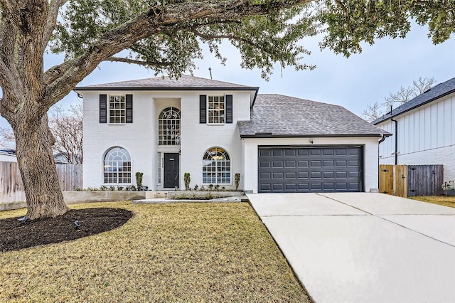 view of front of home featuring roof with shingles, concrete driveway, a front yard, fence, and a garage